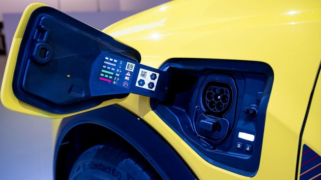 Une Renault 5 E-Tech jaune branchée à une borne de recharge électrique en ville.