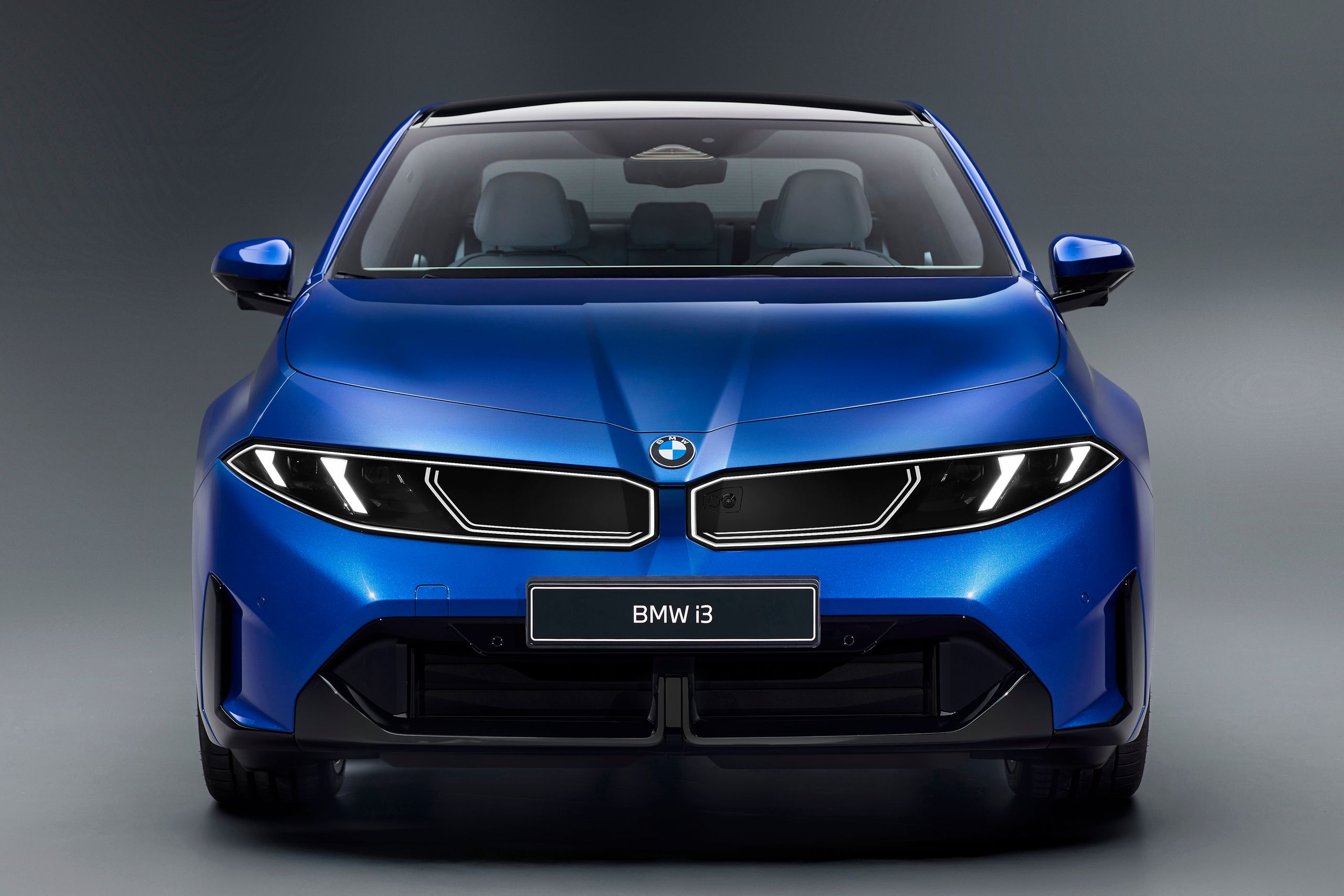 Image d'une BMW i3 50 xDrive 2026 de couleur métallisée, garée dans un environnement urbain moderne, mettant en avant son design élégant et futuriste.