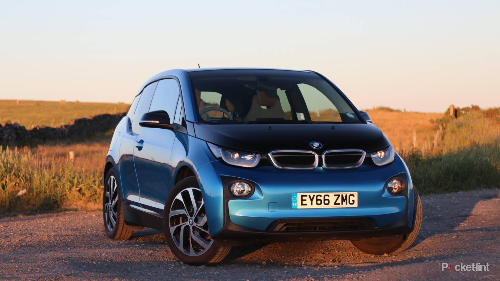 Une BMW i3 de première génération roulant sur une route mouillée, avec des éclaboussures d'eau.