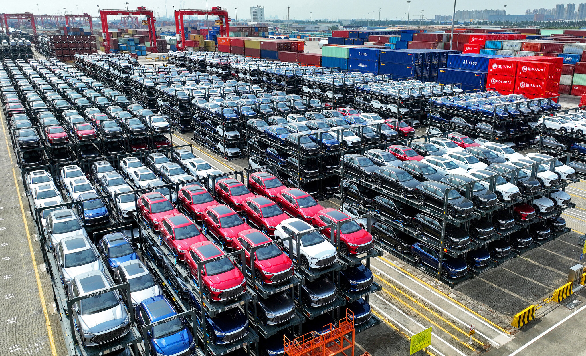 Vue aérienne d'une immense usine de voitures électriques BYD en Chine, montrant des centaines de véhicules en production.
