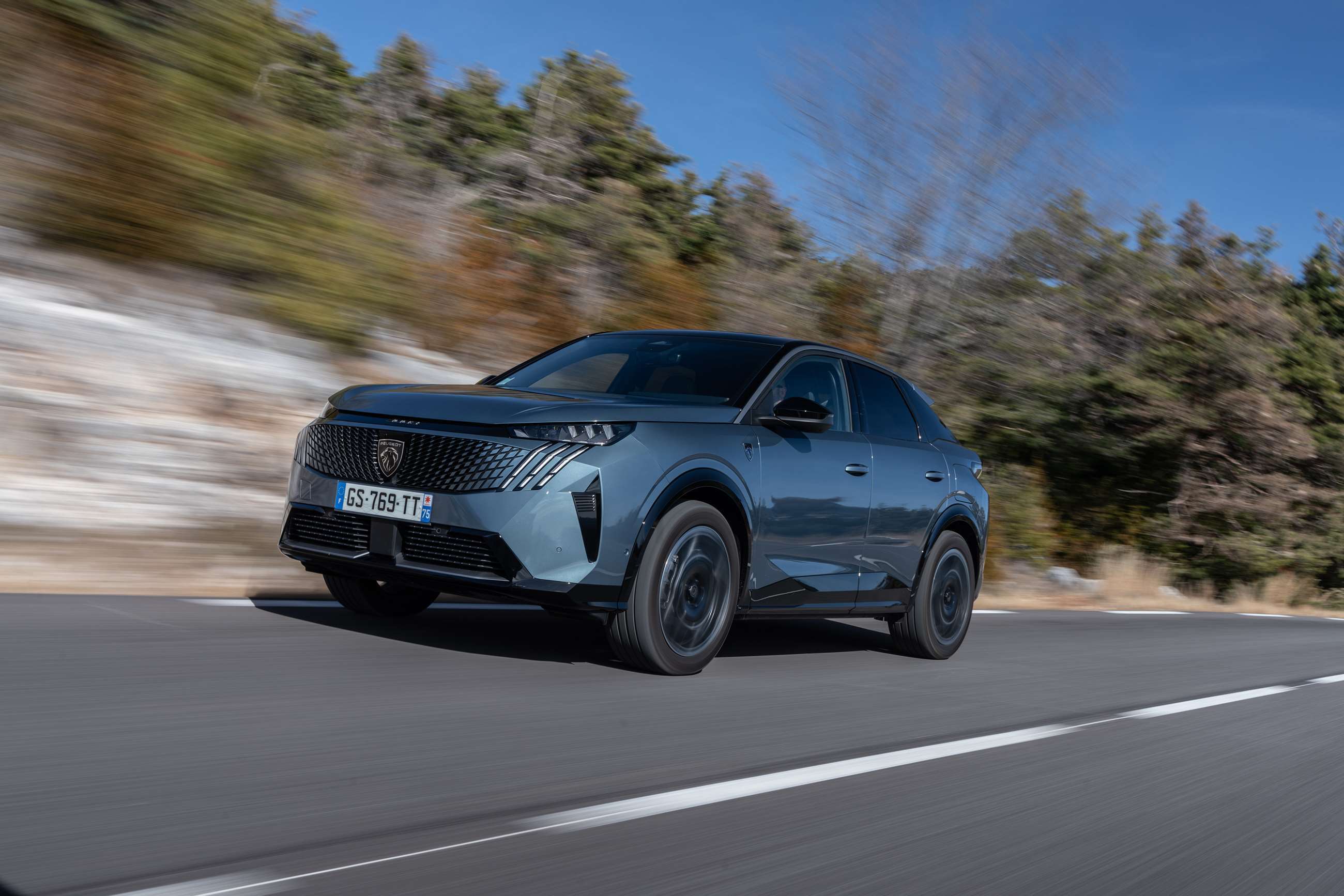 Un SUV Peugeot e-3008 électrique roulant sur une autoroute, symbolisant l'évolution des véhicules électriques familiaux.