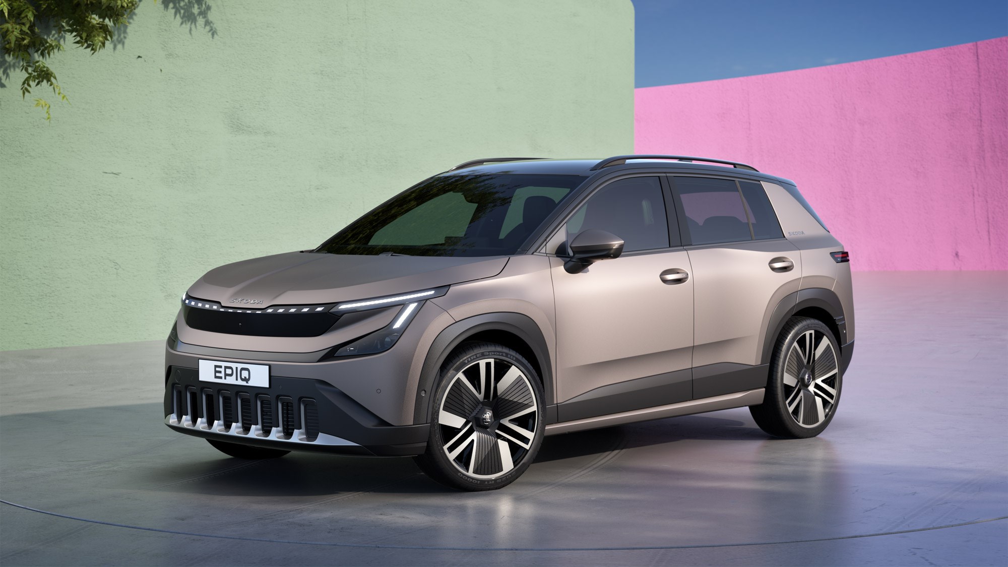 Un Skoda Epiq 2026 bleu, SUV compact électrique, roulant sur une route de campagne sinueuse avec un paysage montagneux en arrière-plan.