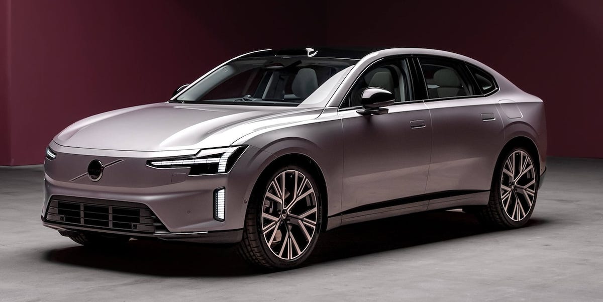 Un SUV électrique Volvo ES90 gris foncé roulant sur une route côtière au coucher du soleil.