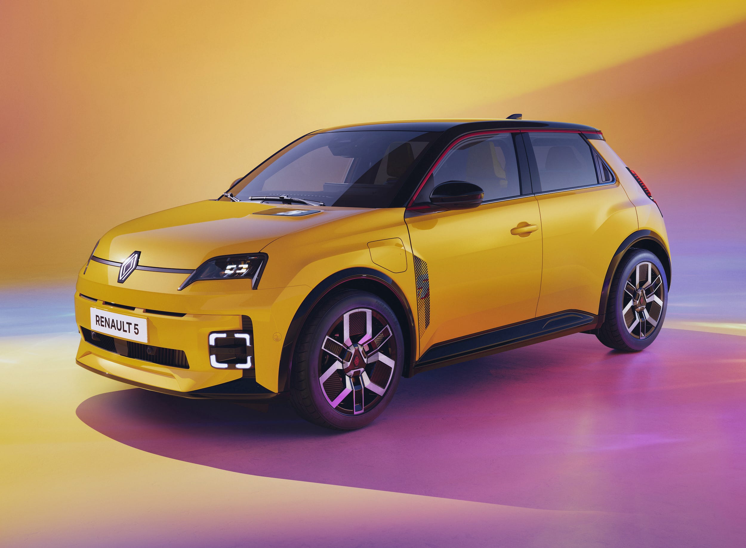 Une Renault 5 E-Tech électrique jaune vif, garée dans une rue pavée d'une ville européenne historique.