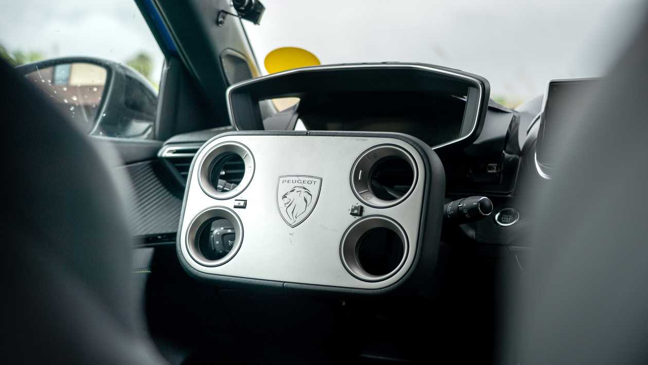 Vue rapprochée du volant Hypersquare futuriste de la Peugeot e-208 génération 3, avec des commandes numériques intégrées.