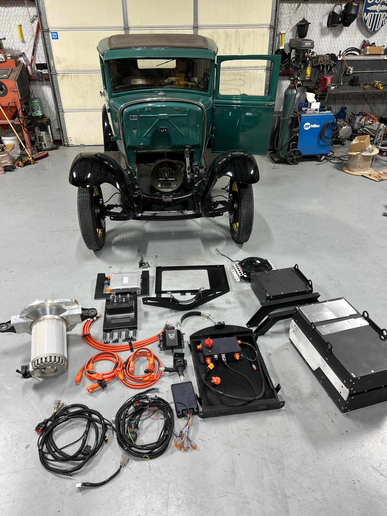 Photo d'un kit de rétrofit pour voiture ancienne, avec un moteur électrique, des batteries et un contrôleur électronique.