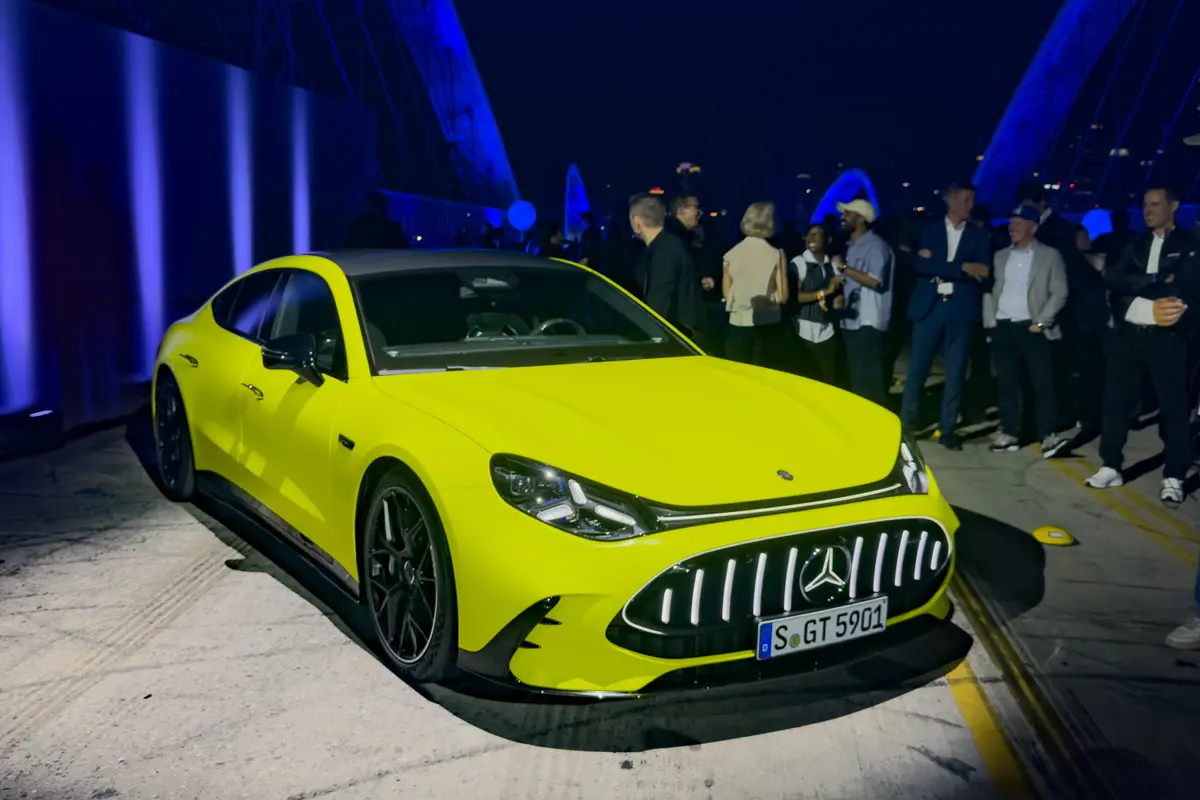 Une Mercedes-AMG GT 4 portes électrique futuriste et élégante, de couleur sombre, avec des lignes aérodynamiques et des phares fins, sur un fond abstrait et technologique.
