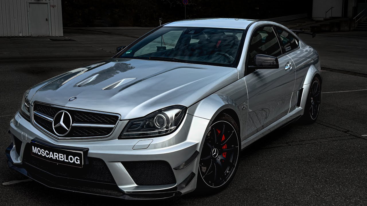 Vue arrière détaillée d'une Mercedes C63 AMG Black Series W204 noire, montrant son grand aileron et son diffuseur, garée sur un circuit automobile.