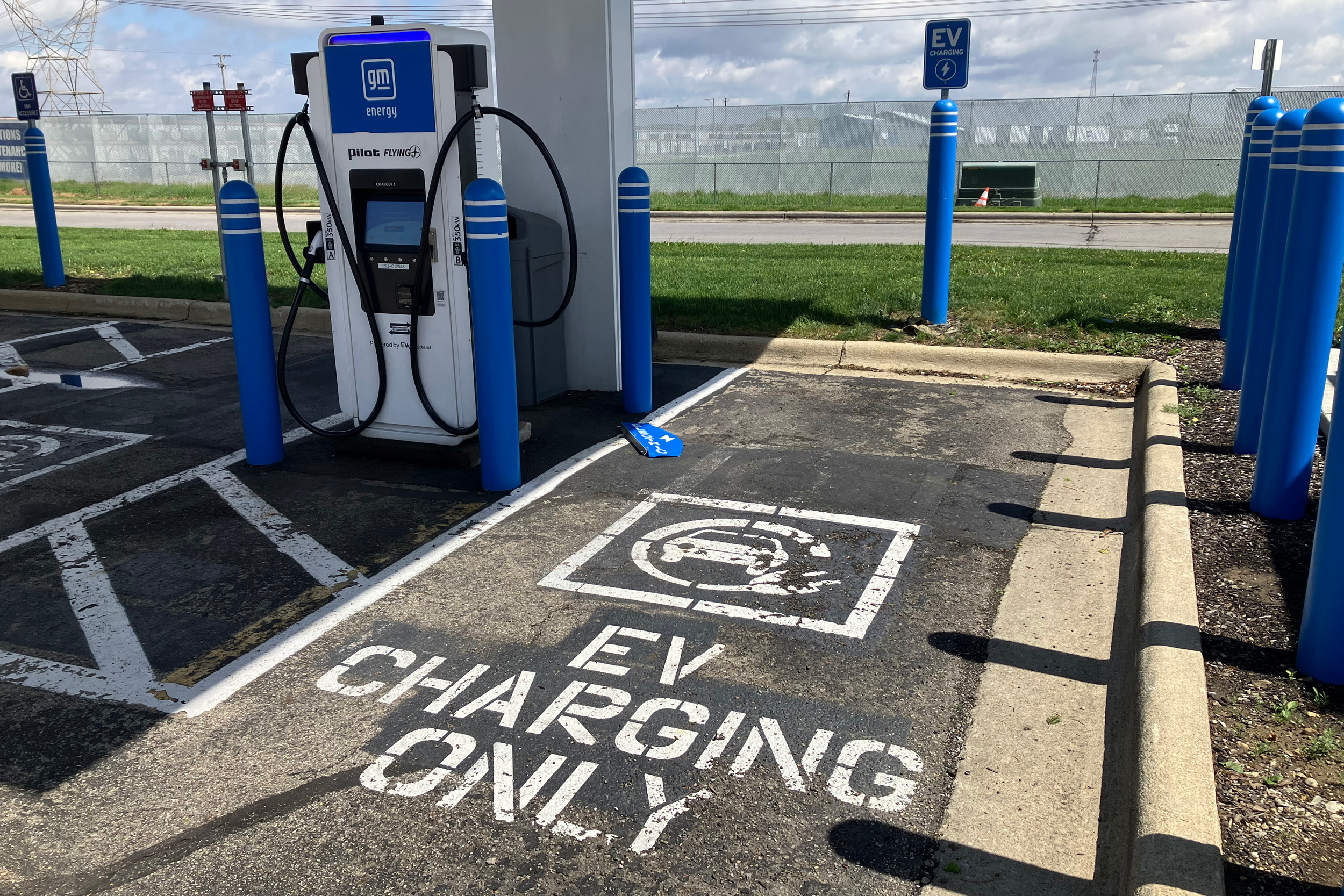 Une voiture électrique en charge à une borne publique, avec des informations sur les subventions affichées numériquement.