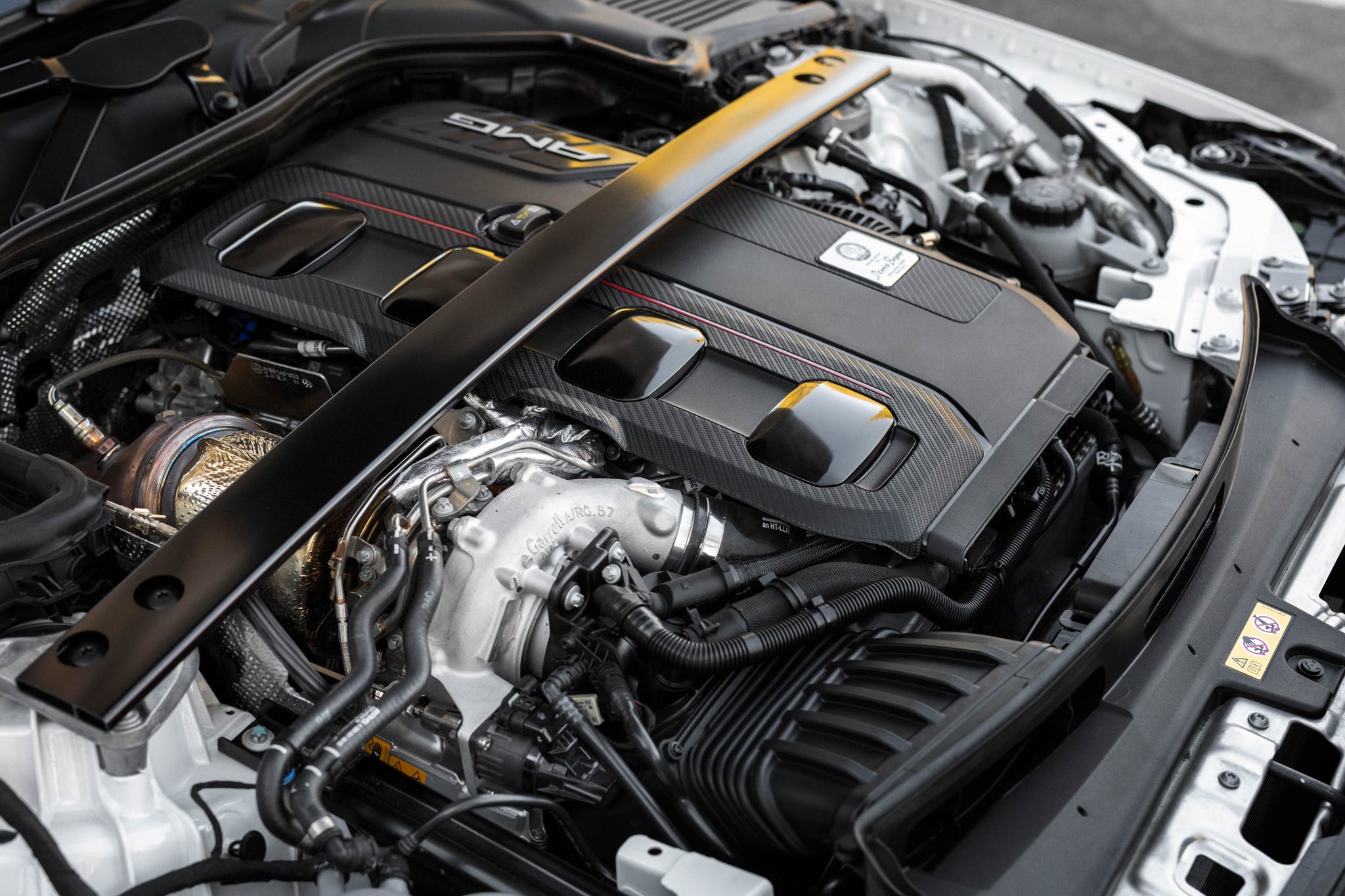 Vue détaillée du compartiment moteur de la Mercedes-AMG C 63 S E-Performance, montrant le moteur hybride et ses composants.