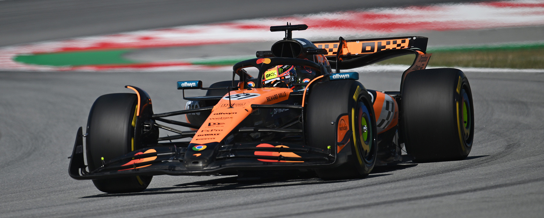 Oscar Piastri dans sa McLaren de Formule 1 en pleine action sur un circuit, avec un arrière-plan flou de vitesse.