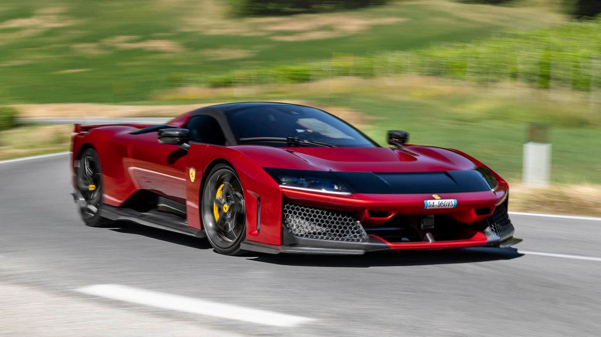 Une Ferrari F80 rouge, hypercar hybride, garée sur une piste de course, montrant ses lignes agressives et son design futuriste.