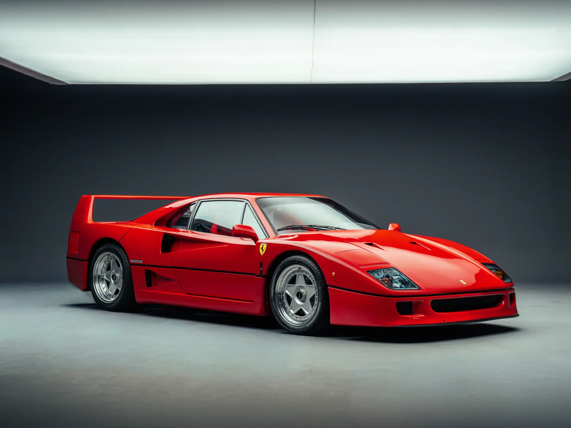 Une Ferrari F40 rouge sur un podium d'enchères, illustrant l'engouement des collectionneurs.