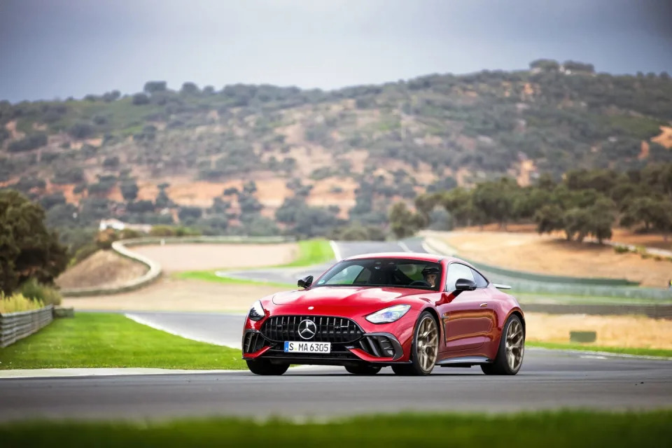 Une Mercedes-AMG GT 63 Pro verte foncée en pleine action sur un circuit, avec de la fumée de pneu et un arrière-plan flou.