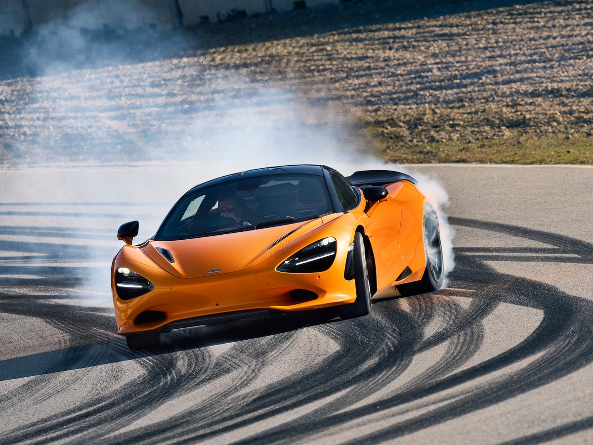 Une McLaren 750S rouge vif en pleine accélération sur une piste de course, l'arrière-plan flou suggérant une vitesse élevée.