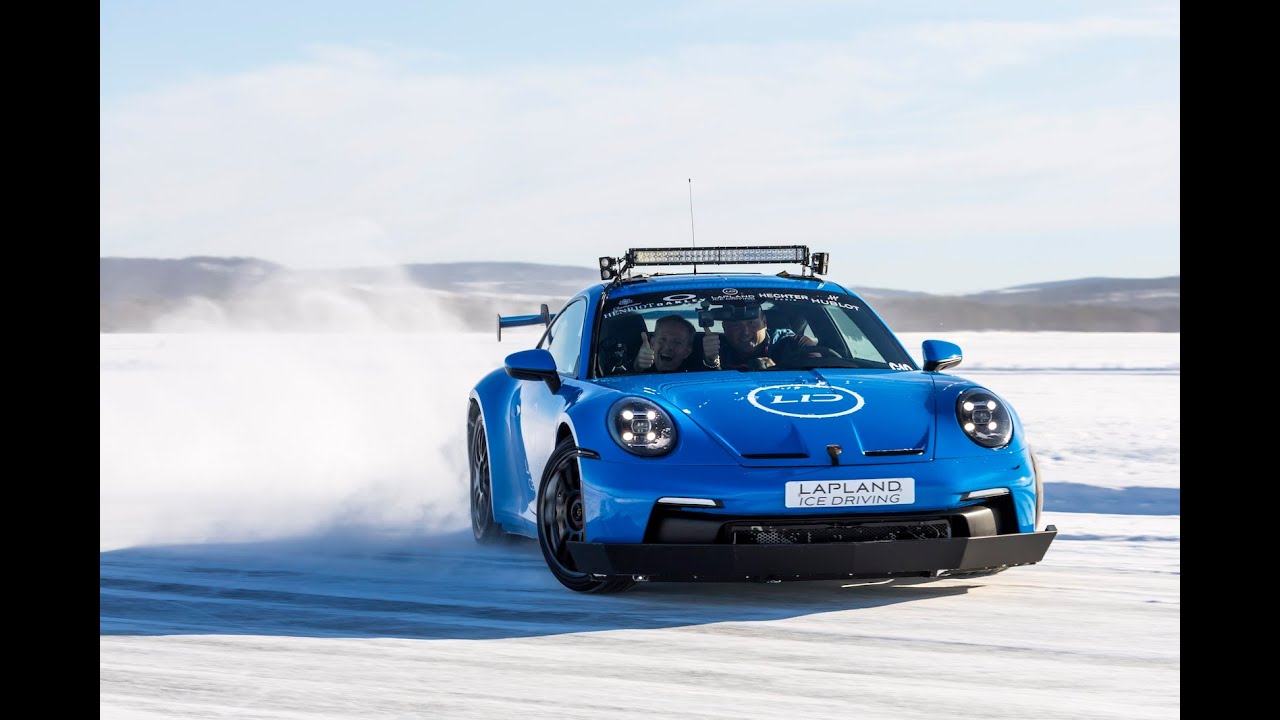 Une Porsche 992 GT3 rouge en train de déraper sur une piste de glace, entourée de neige.