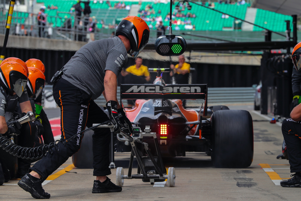 Équipe de stand McLaren en pleine action, effectuant un arrêt au stand rapide et précis sur une voiture de Formule 1.