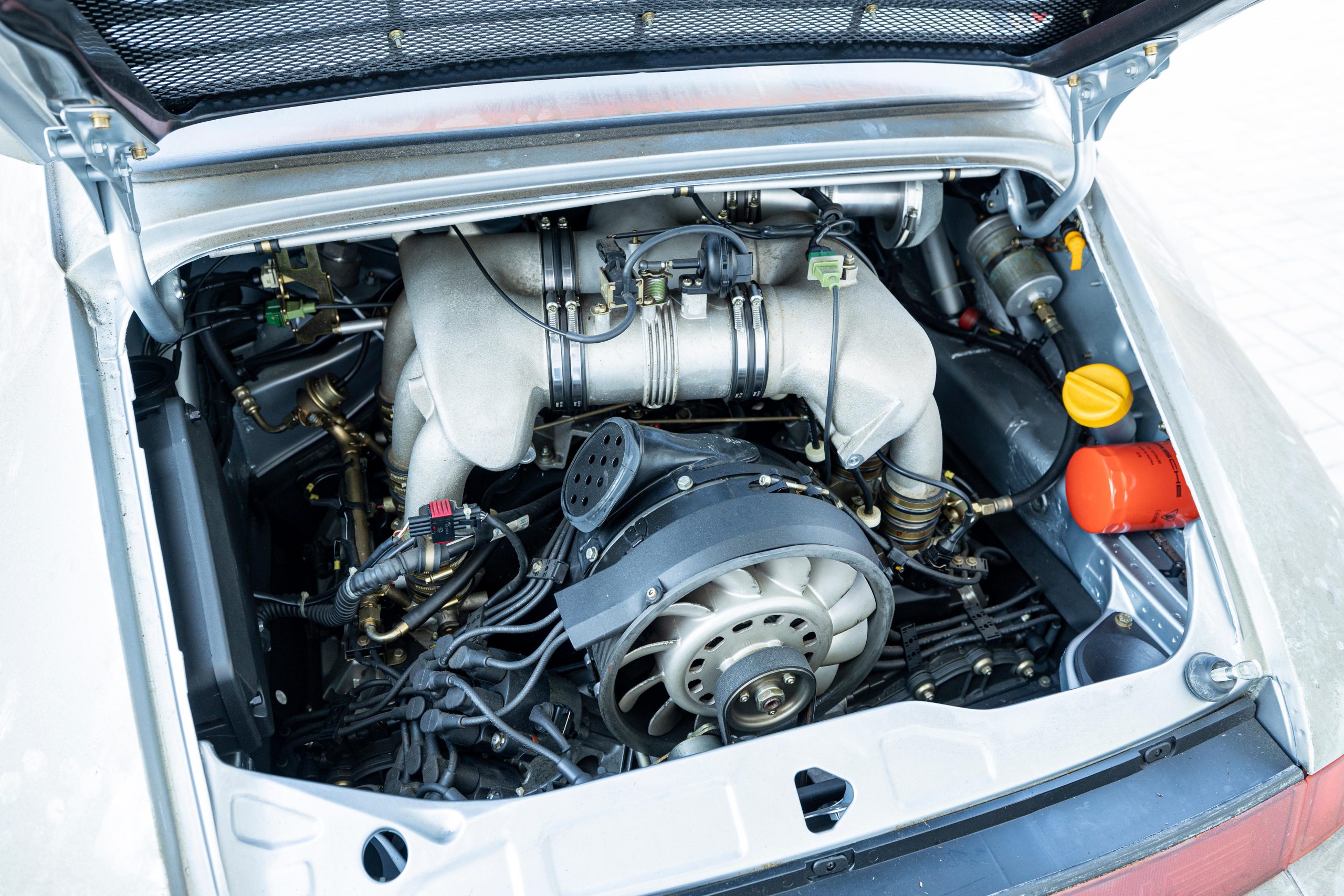 Vue détaillée du moteur six cylindres à plat de 3,8 litres de la Porsche 911 Carrera RSR 3.8, avec ses collecteurs d'admission et ses composants mécaniques visibles.