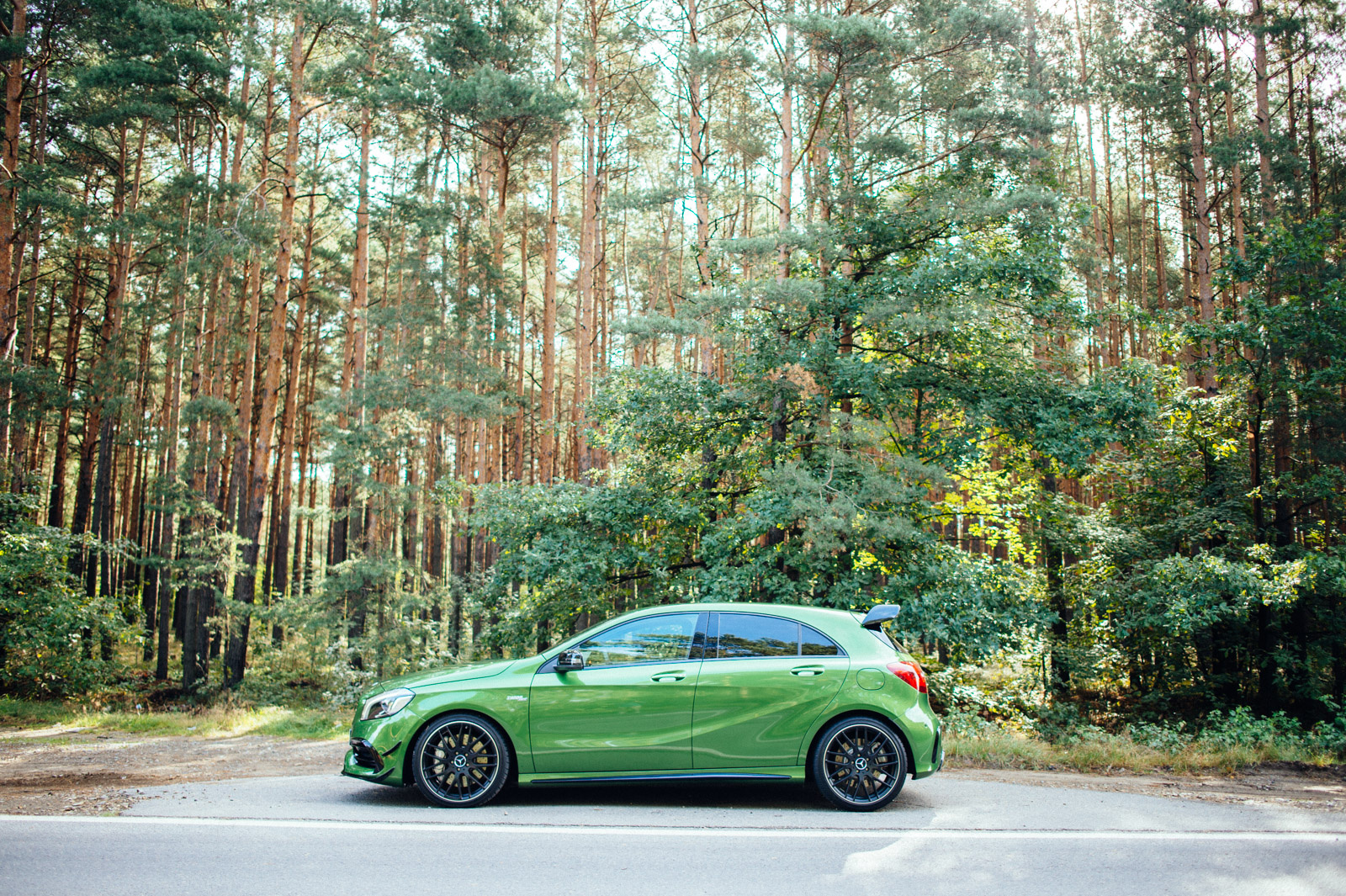 Une Mercedes-AMG A45 argentée en mouvement sur une route de campagne, vue d'en haut.