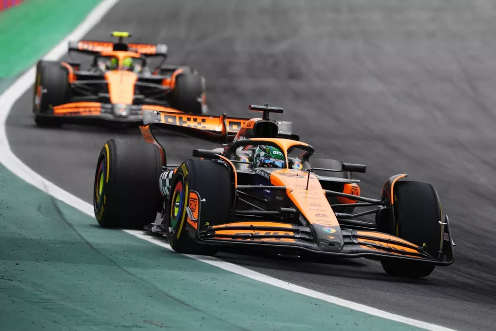 Lando Norris et Oscar Piastri pilotant leurs McLaren MCL38 à grande vitesse sur un circuit de Formule 1.