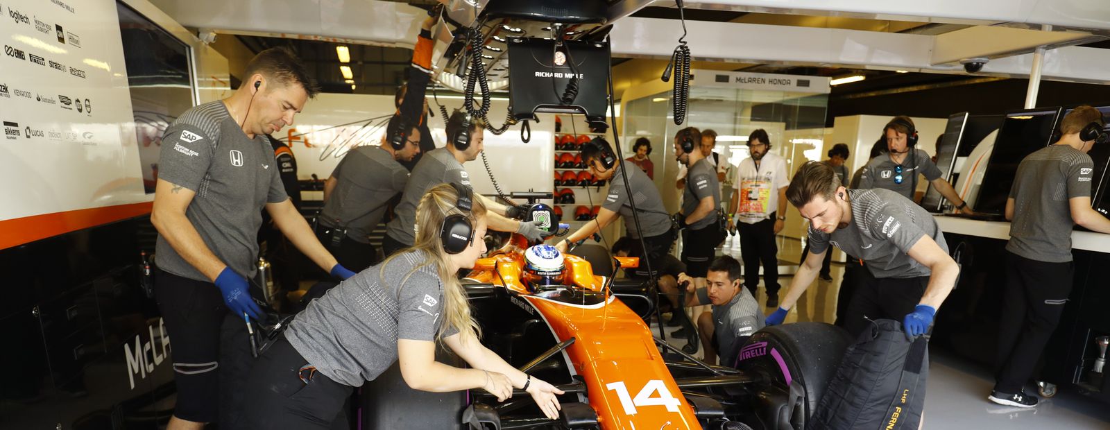 Des stratèges de l'équipe McLaren de Formule 1 dans un garage, concentrés sur des écrans de données.