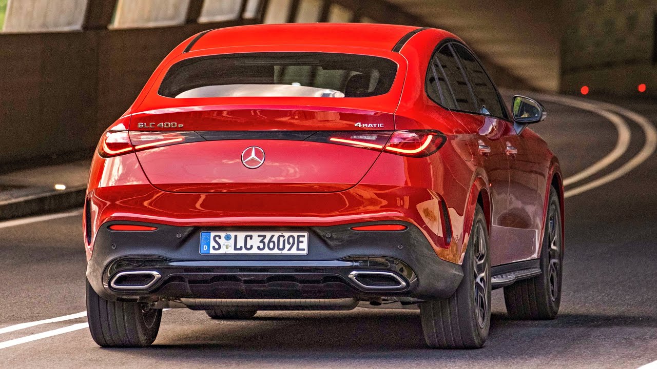 Un Mercedes-AMG GLC Coupe 400 e 4Matic en mouvement sur une route sinueuse, avec un paysage montagneux en arrière-plan.