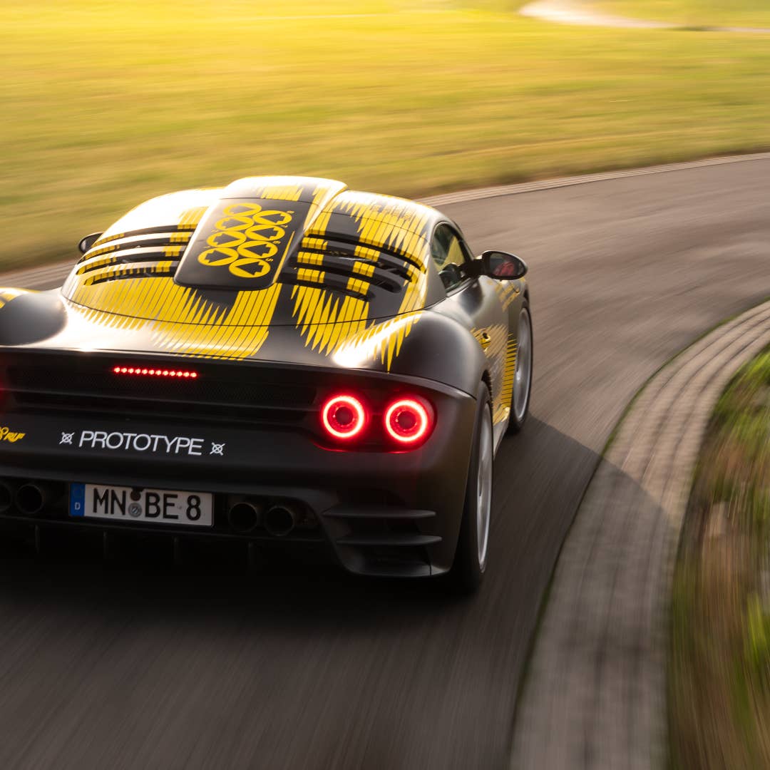Vue latérale de la supercar Ruf roulant à grande vitesse sur une piste, avec un arrière-plan flou de mouvement.