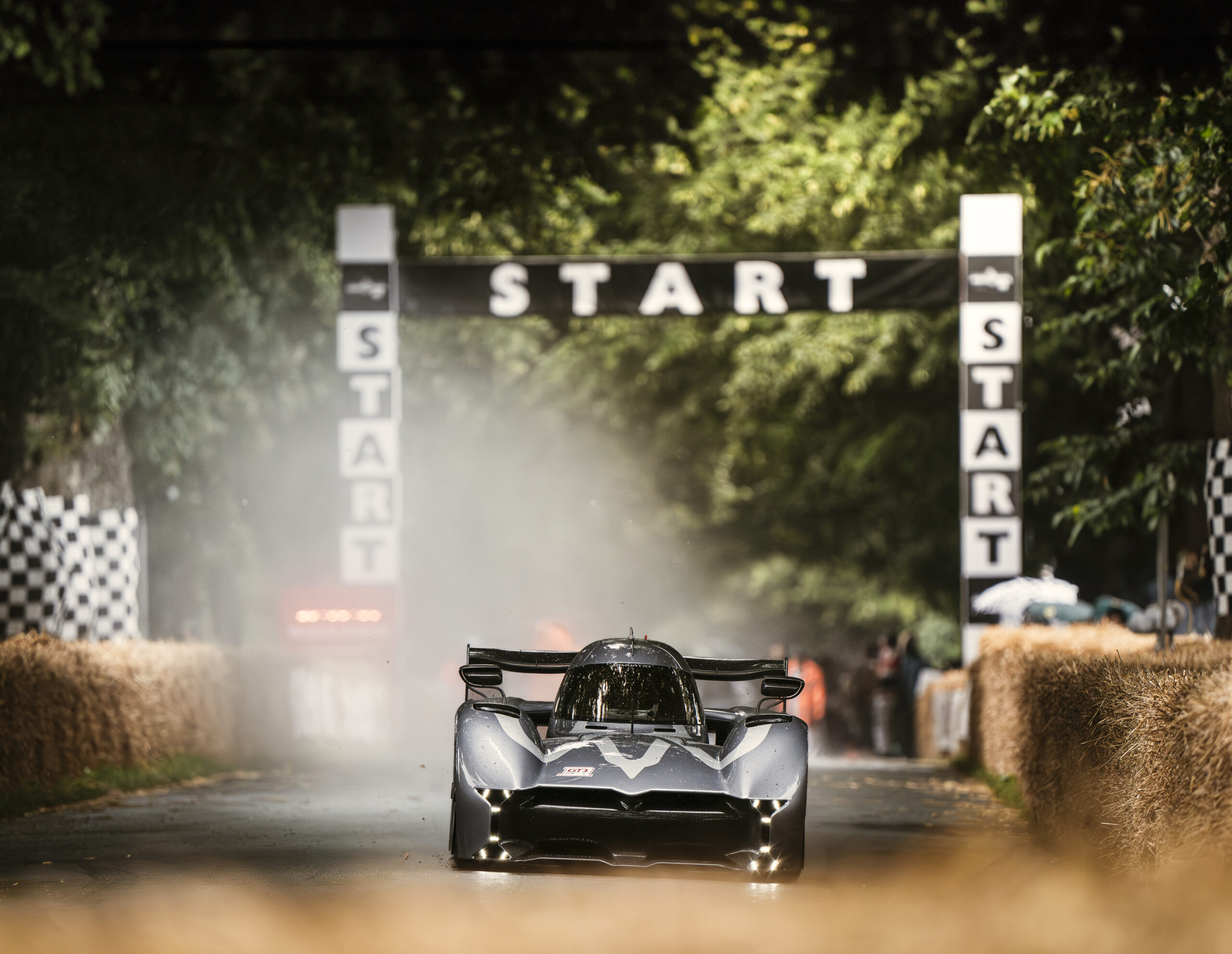 La McMurtry Spéirling Pure, une hypercar électrique noire et aérodynamique, monte la célèbre côte de Goodwood, laissant une traînée de poussière derrière elle.