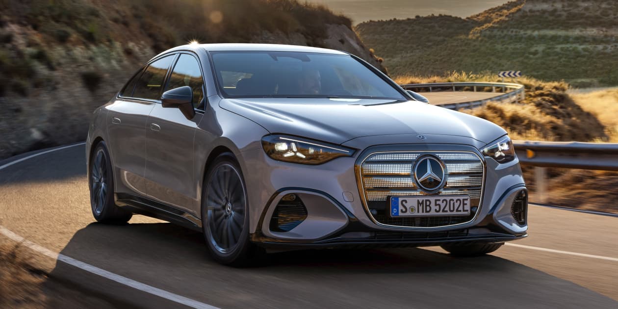 Une Mercedes C 400 4MATIC électrique blanche roulant sur une route sinueuse avec un paysage montagneux en arrière-plan.