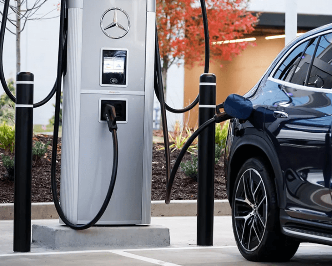 Une Mercedes Classe C électrique grise connectée à une borne de recharge rapide, avec l'indicateur de charge allumé.