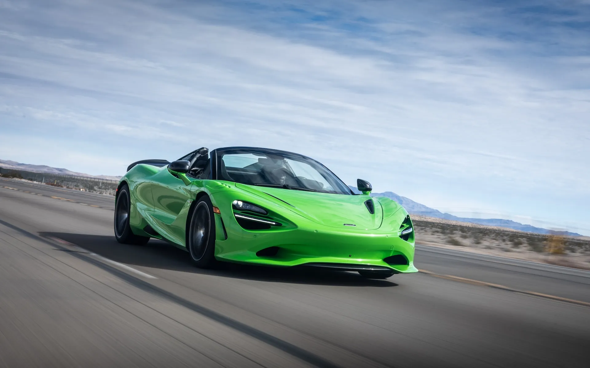 Une McLaren 750S orange vif en pleine accélération sur une piste de course, floue de mouvement.