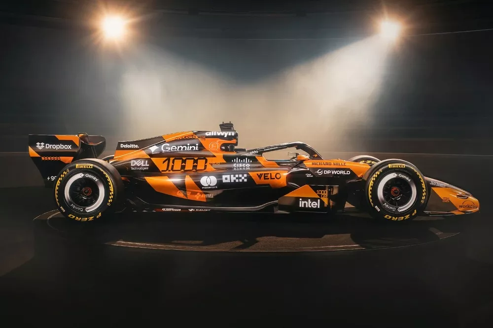 Une voiture de Formule 1 McLaren orange et noire négociant un virage serré à Monaco, avec des yachts et des bâtiments en arrière-plan.