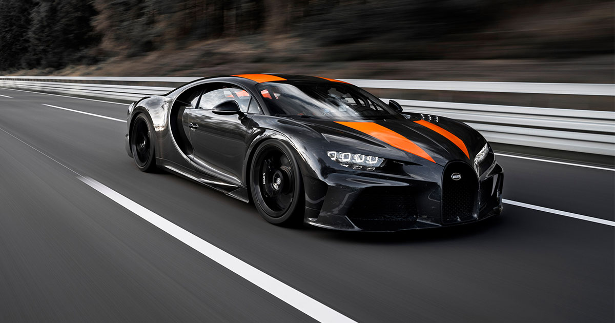 Une Bugatti Chiron Super Sport 300+ jaune et noire roule sur une route côtière sinueuse à Penghu, avec la mer et des falaises en arrière-plan.