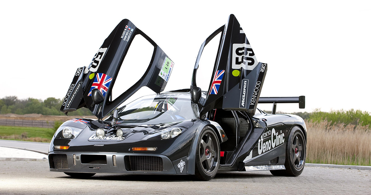 Une McLaren F1 GTR de couleur vive sur la piste lors du Mans Classic, avec d'autres voitures de course classiques en arrière-plan.