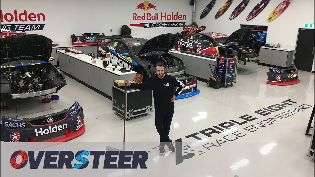 Des mécaniciens de l'équipe Triple Eight Race Engineering travaillant sur des Supercars dans un garage.