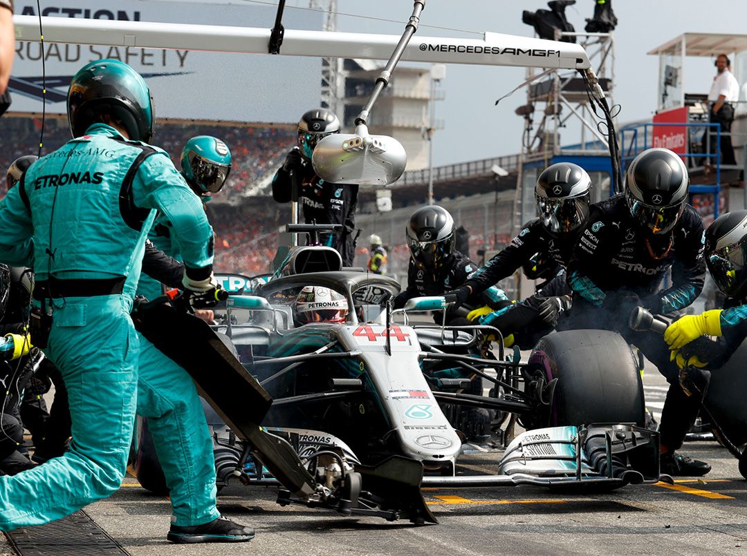 Mercedes-AMG One sur une piste de course avec une équipe de mécaniciens en arrière-plan, illustrant la maintenance spécialisée.