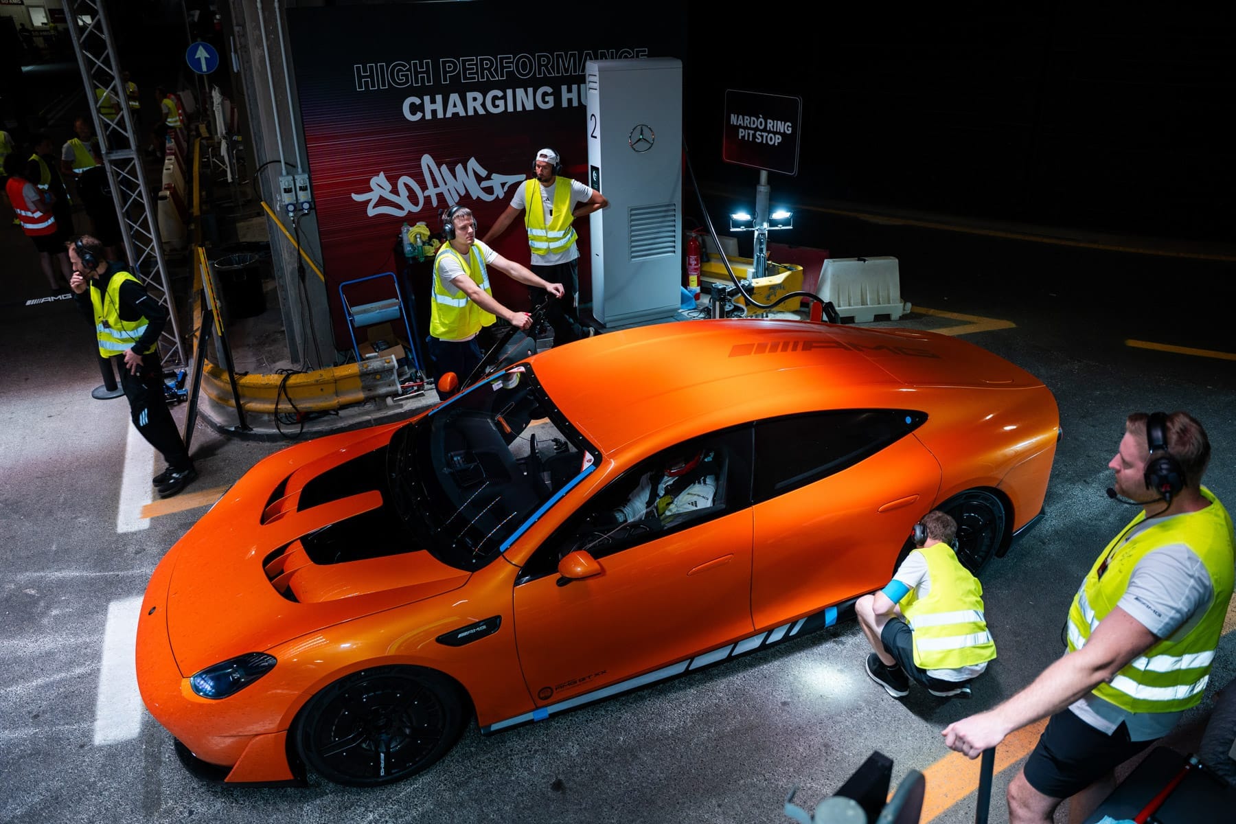 Une Mercedes-AMG électrique de grand tourisme branchée à une borne de recharge rapide, avec des lumières bleues indiquant le flux d'énergie.