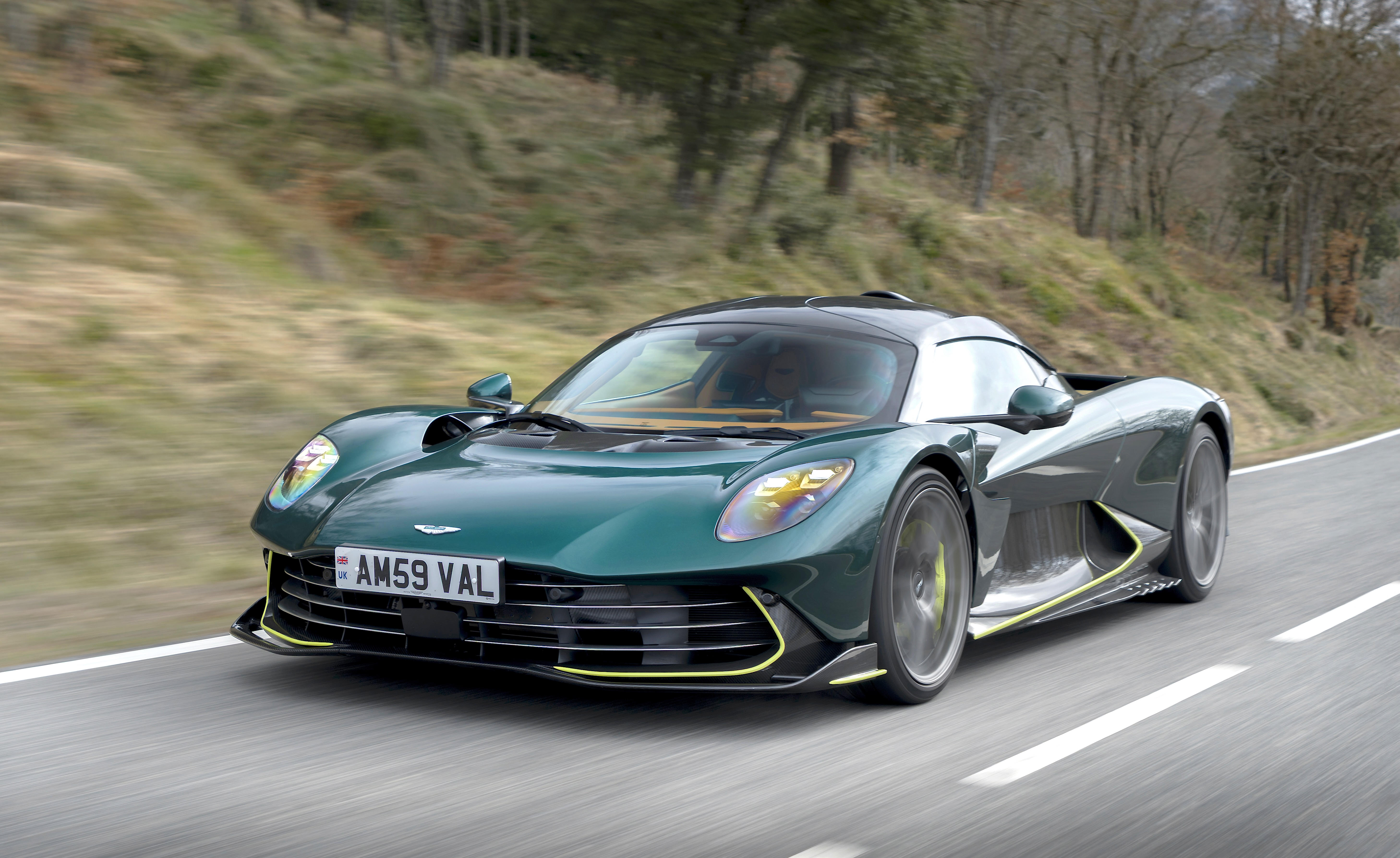 Une supercar de 2026 avec des suspensions actives et prédictives ajustant la hauteur de caisse et l'amortissement en temps réel sur une route sinueuse.