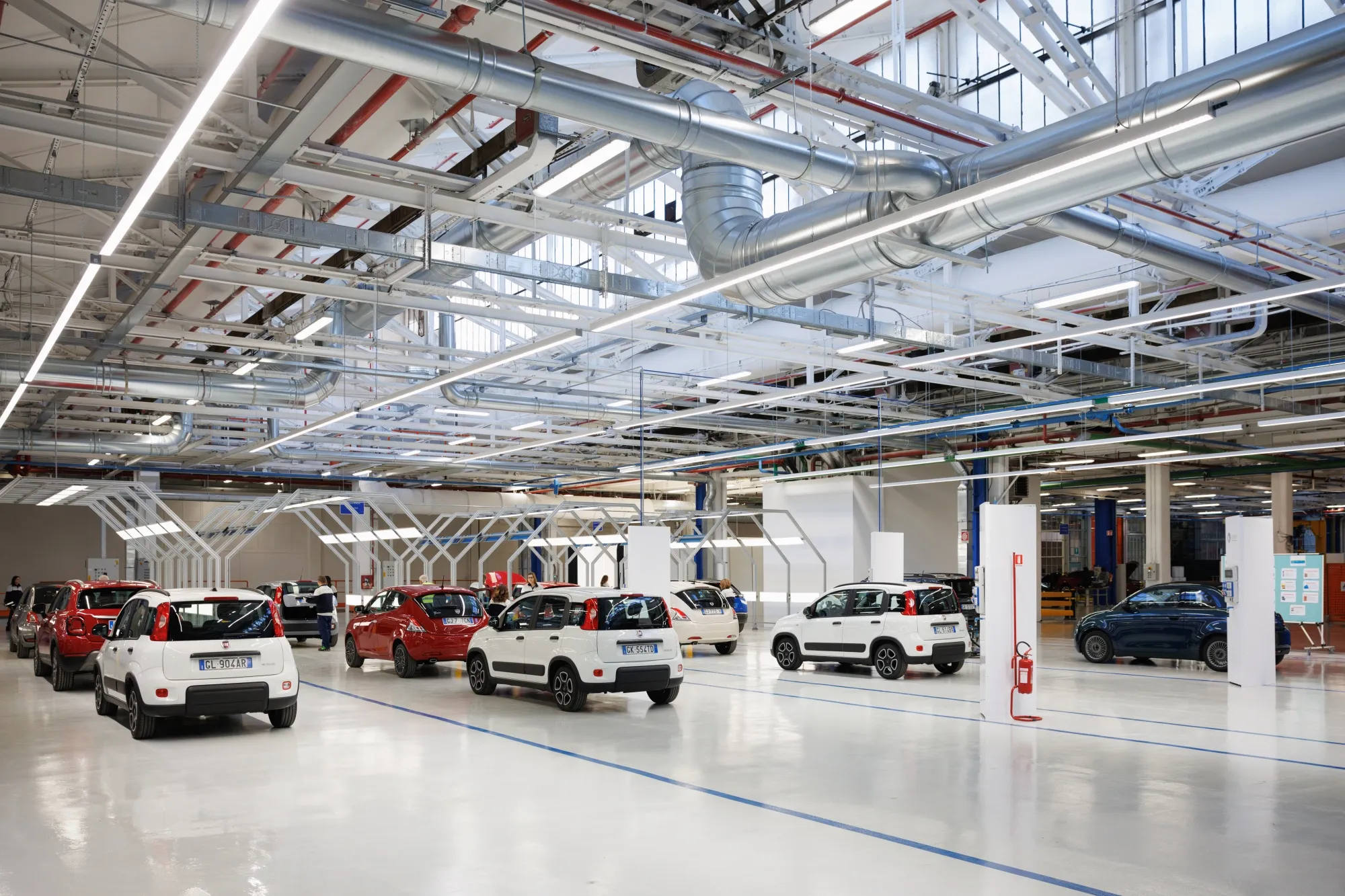 Vue d'une usine Stellantis en Italie, montrant des robots assemblant des voitures sur une chaîne de production.