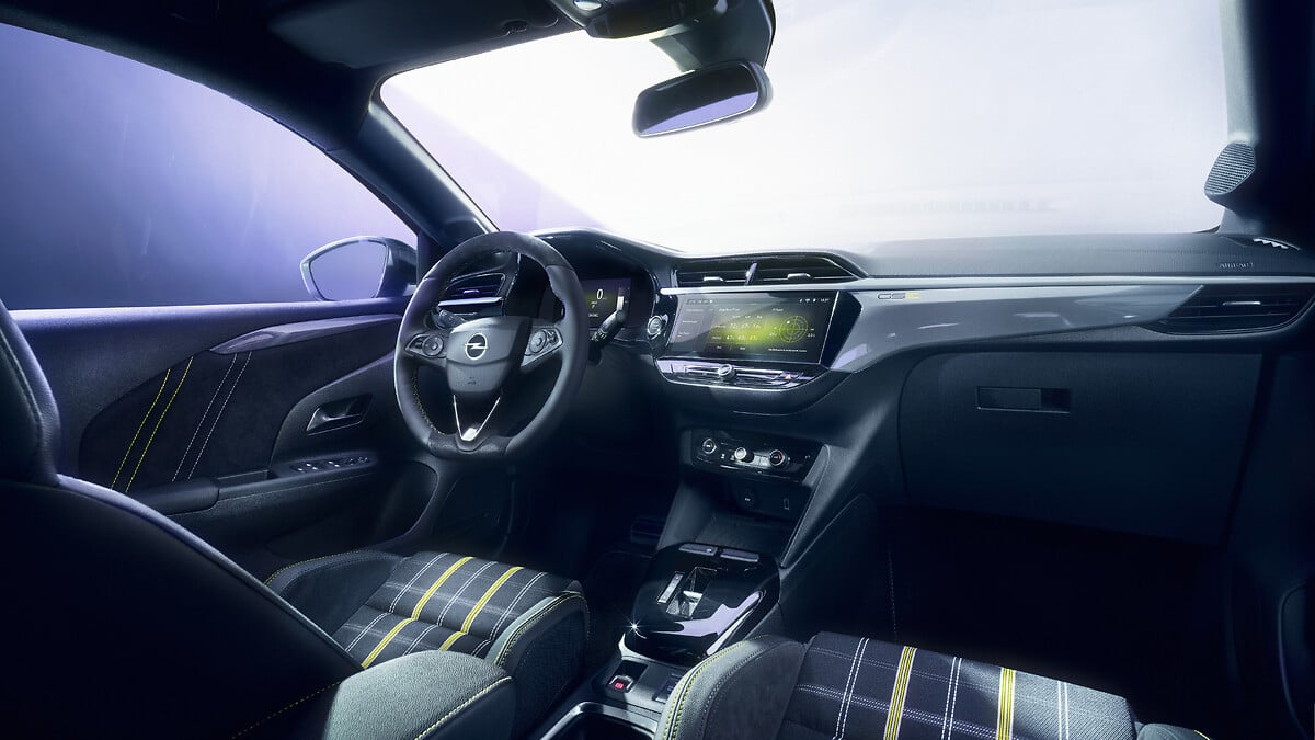 L'intérieur de l'Opel Corsa GSE, montrant le tableau de bord numérique, l'écran tactile central, le volant sport et les sièges baquets avec un motif écossais.