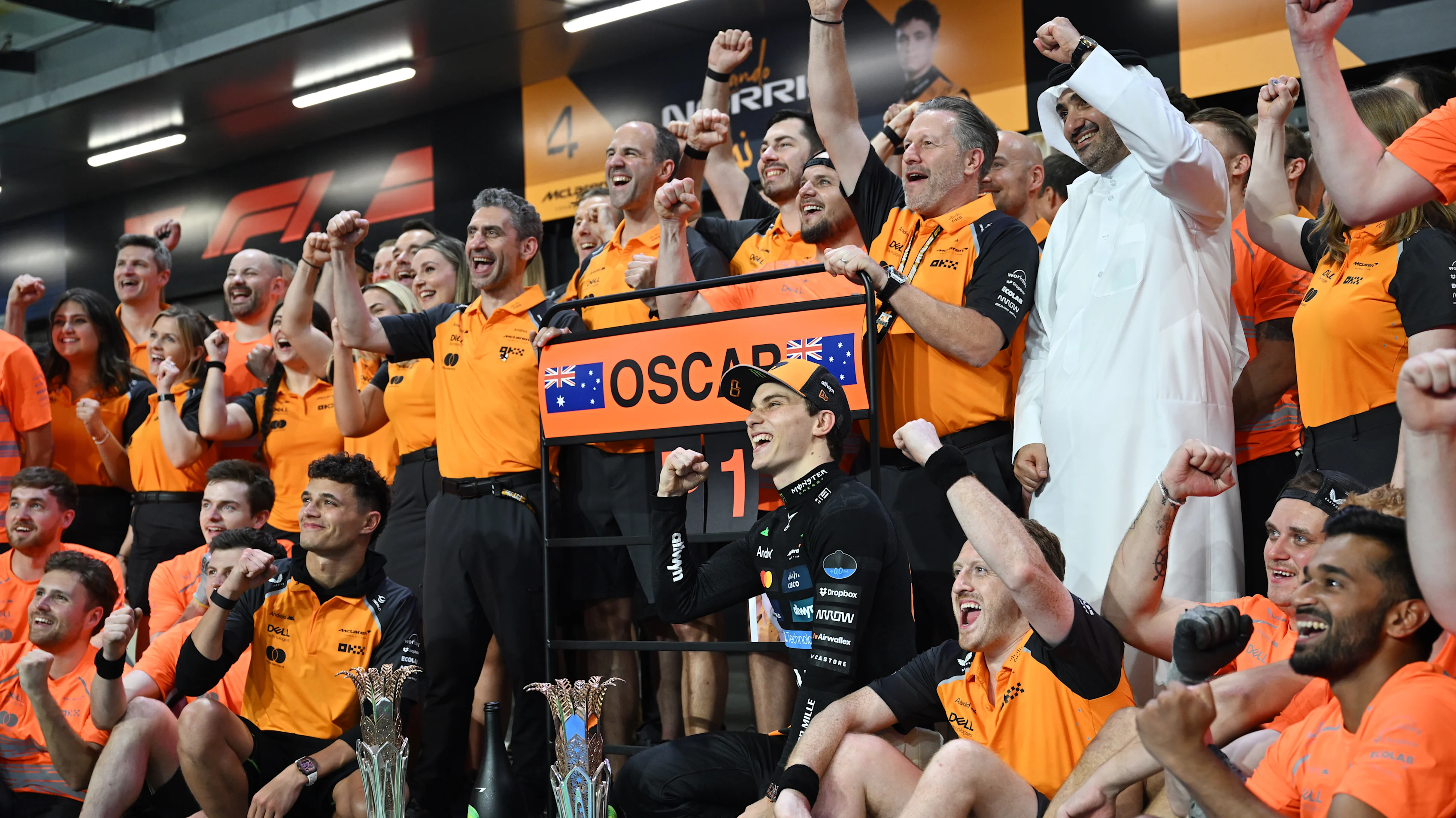 Des ingénieurs de l'équipe McLaren de Formule 1 concentrés sur leurs écrans au muret des stands.