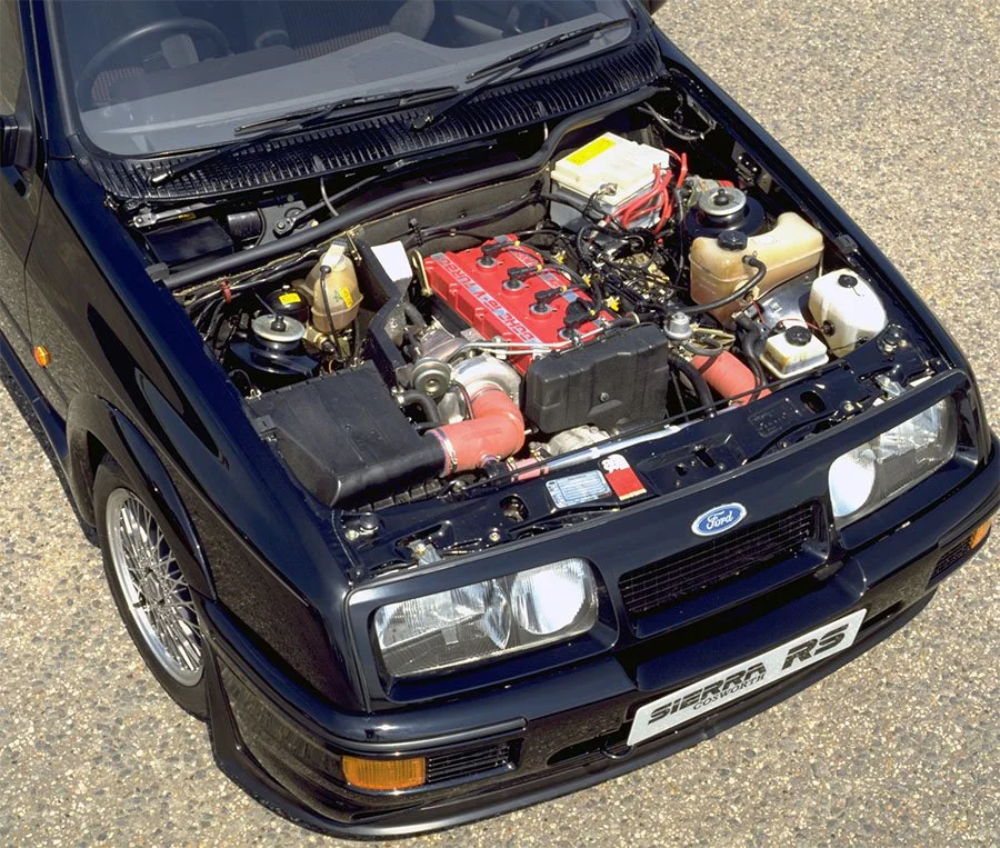 Vue détaillée du compartiment moteur d'une Ford Sierra RS500 Cosworth, montrant le moteur Cosworth YB avec ses composants distinctifs.