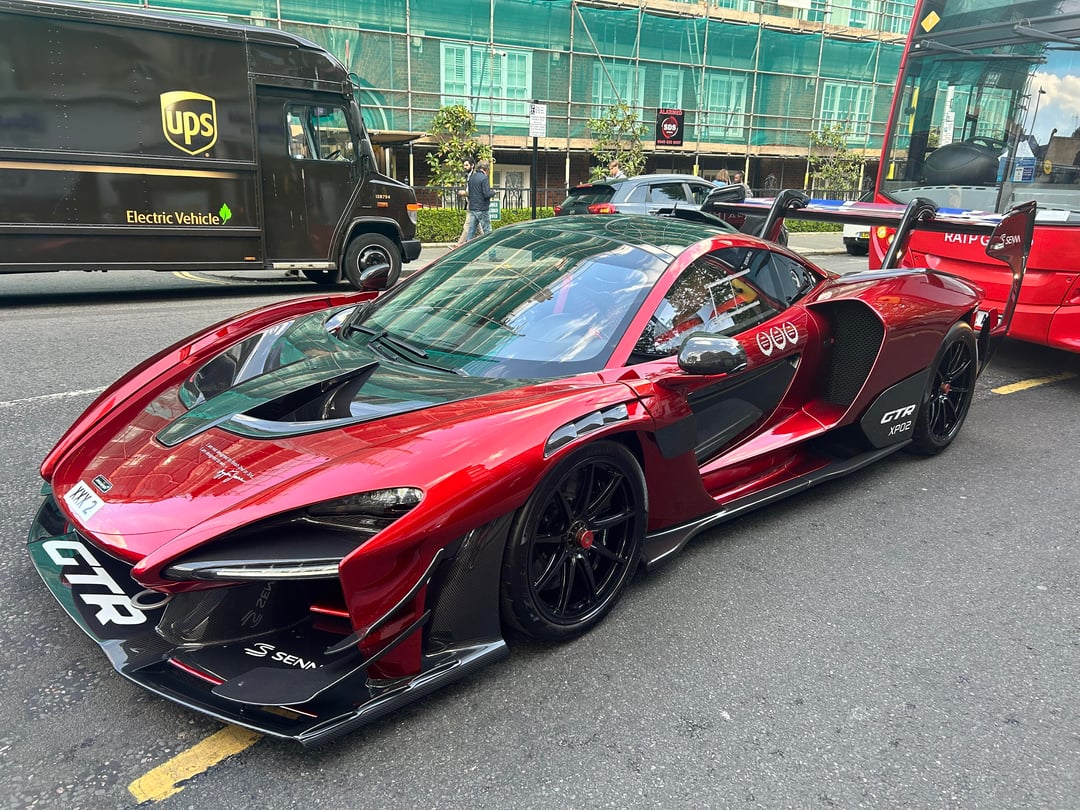 Une McLaren Senna GTR noire mate avec des motifs Kaws colorés, garée dans une rue élégante de Londres.