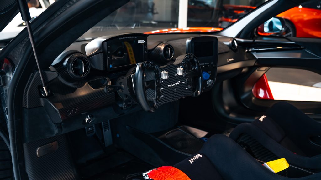 L'intérieur d'une McLaren Senna GTR avec des sièges baquets en carbone et des motifs Kaws sur le tableau de bord.