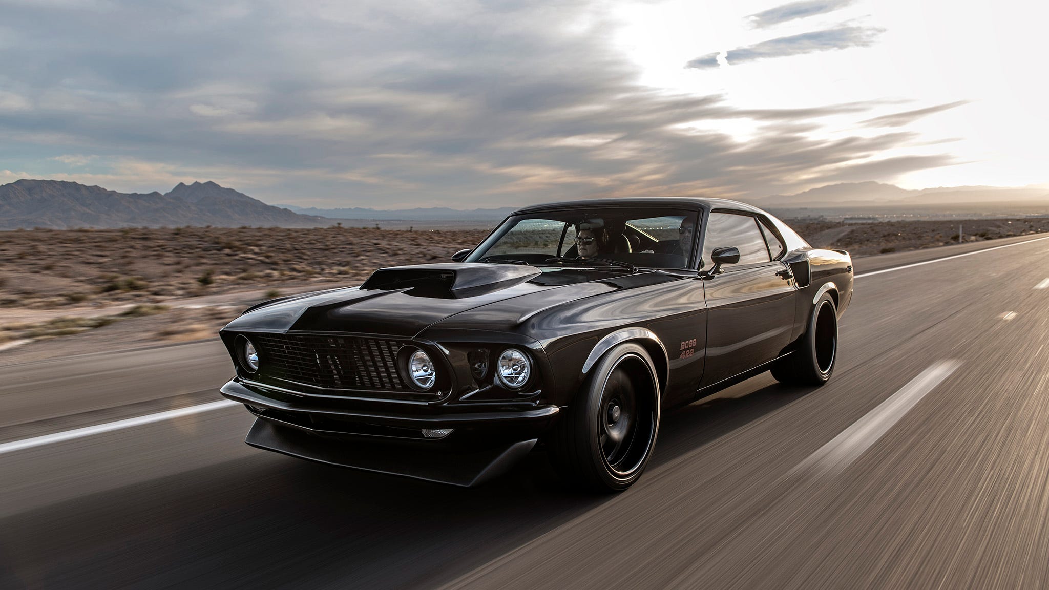 Une Ford Mustang Boss 429 bleue de 1969, roulant sur une route de campagne.
