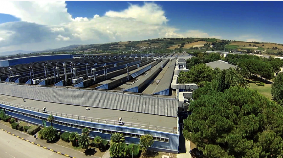 Vue aérienne d'un complexe industriel Stellantis en Europe, avec plusieurs bâtiments et des voitures garées.