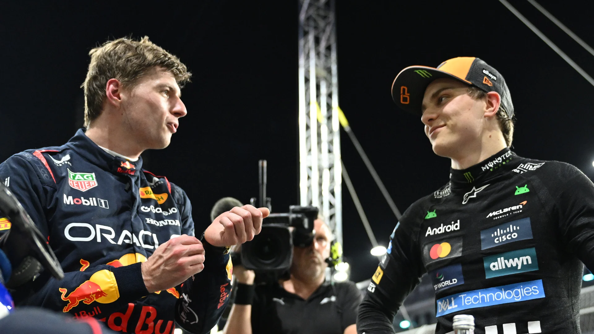 Oscar Piastri et Max Verstappen, côte à côte sur une piste de Formule 1, en tenue de course.