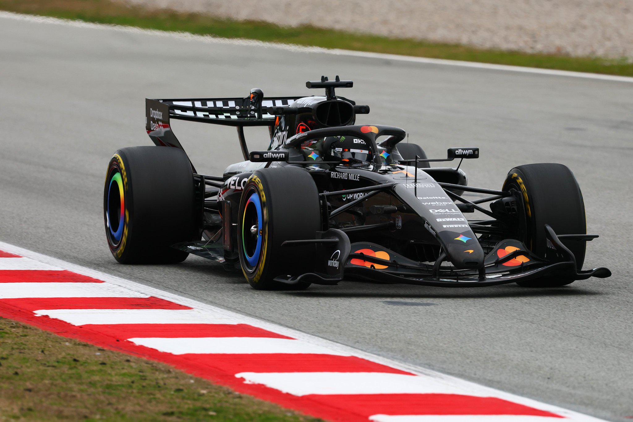 La McLaren MCL40 négociant un virage à grande vitesse sur un circuit de Formule 1, avec un flou de mouvement.