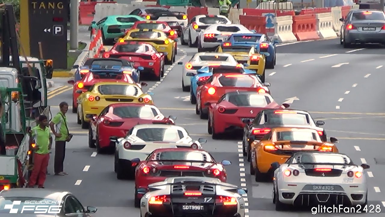 Des hypercars de luxe sont bloquées dans un embouteillage, entourées de voitures ordinaires et de piétons, sur une rue de ville animée.
