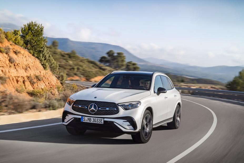 Un Mercedes-AMG GLC 43 blanc roulant sur une route sinueuse, avec un paysage montagneux en arrière-plan.
